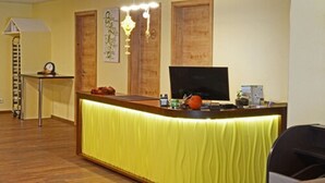 A reception area with a desk, a television, and a chandelier.