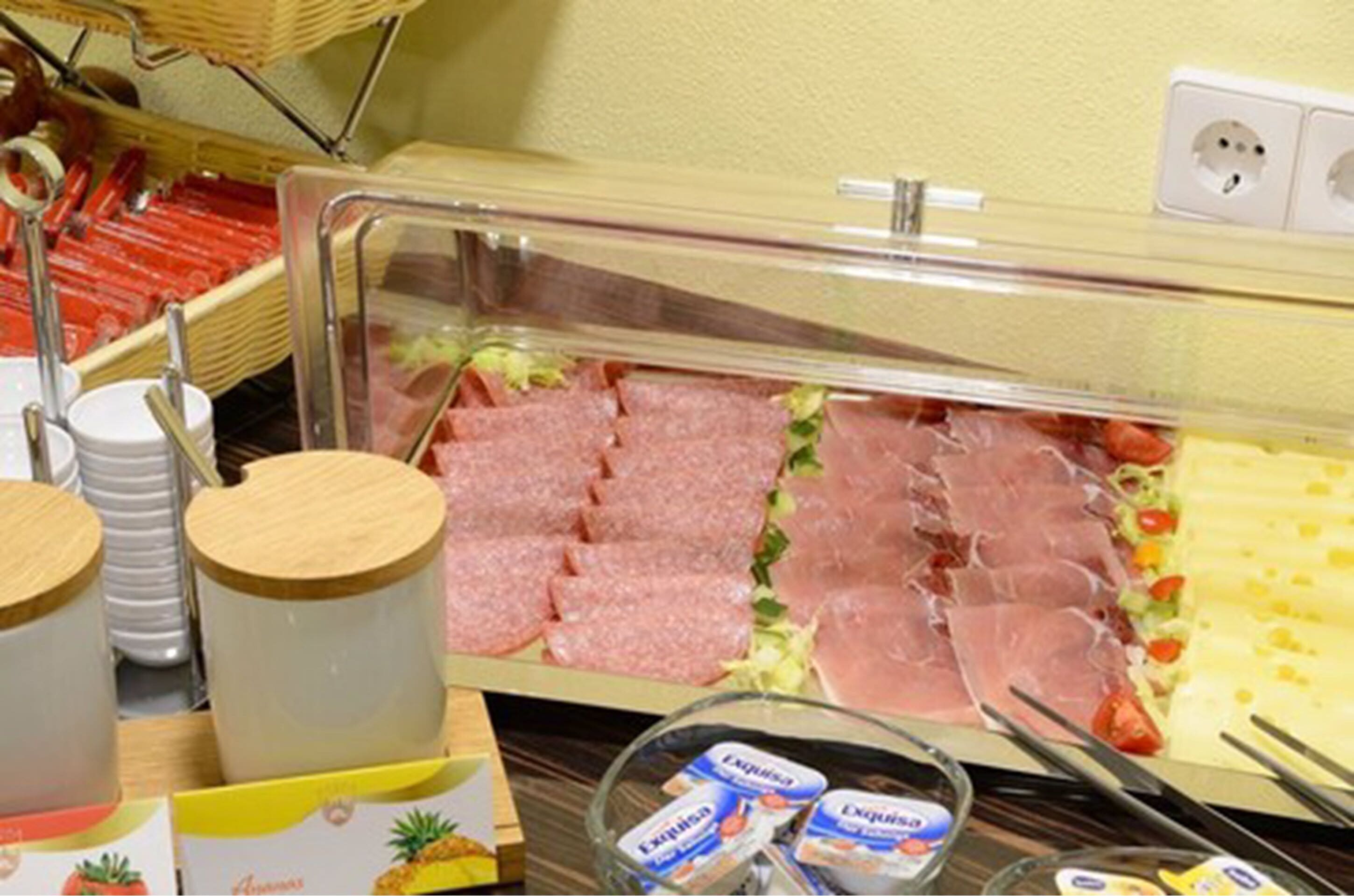 Een buffet met diverse vleessoorten, kazen en sauzen.