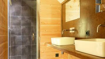 Un baño moderno con paredes de madera, cabina de ducha de vidrio y un espejo grande sobre el lavabo.