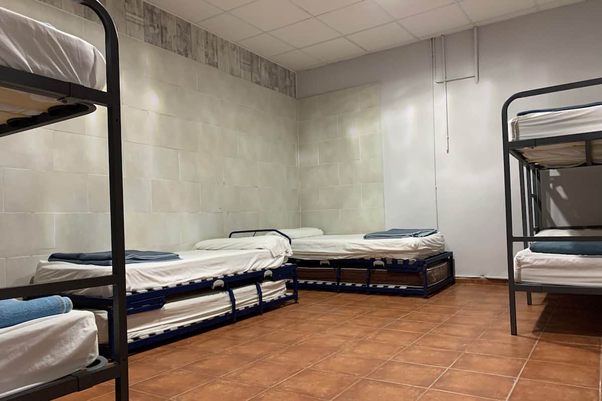 A dormitory room with bunk beds, tiled walls, and a tiled floor.