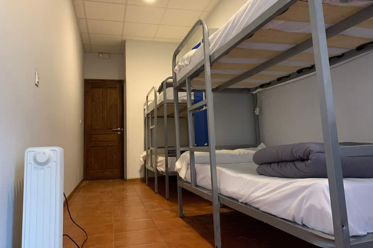 A dormitory room with bunk beds, a wooden door, and a radiator.