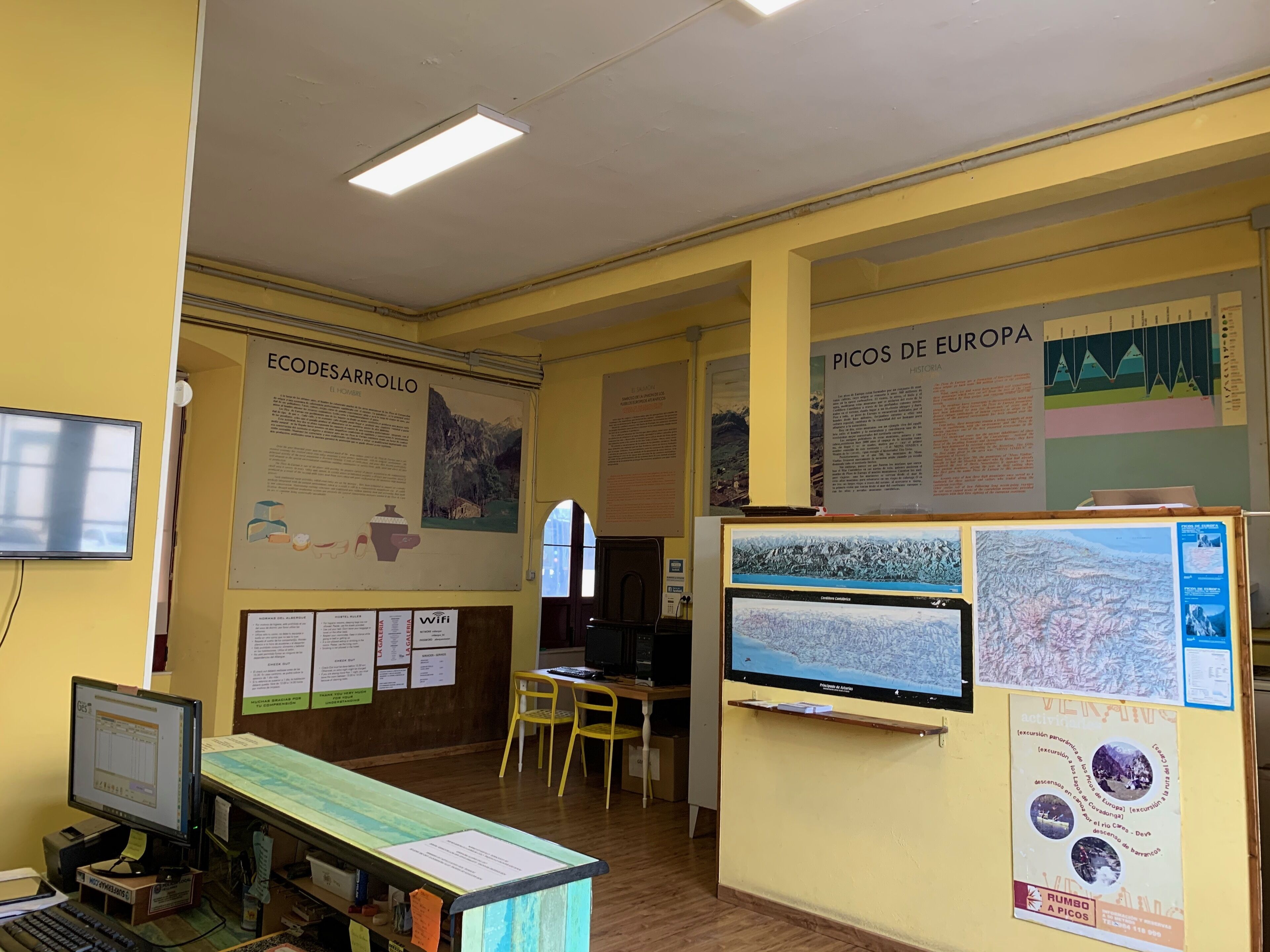 A room with a computer, a desk, chairs, and informational posters on the walls.