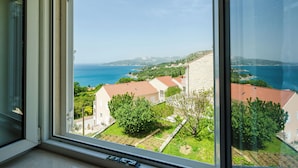 A view from a window overlooking a coastal area with houses, greenery, and the sea.