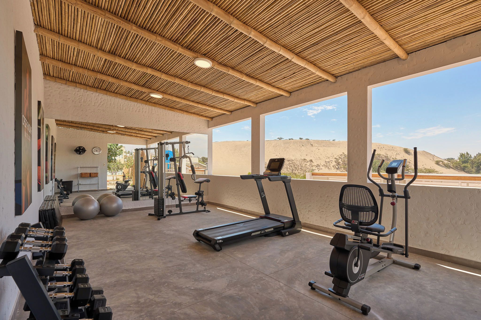 Un gimnasio con equipo de ejercicio, cinta de correr y pesas.