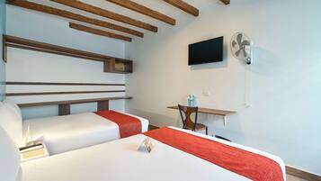 Una habitación de hotel con dos camas, televisión, ventilador y una mesita.