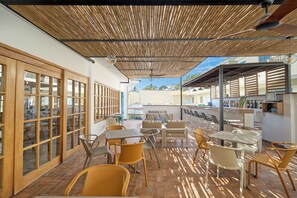 An outdoor patio area with tables and chairs, a wooden ceiling, and a view of the surrounding buildings. - Casa Andina Standard Ica   (Ica)