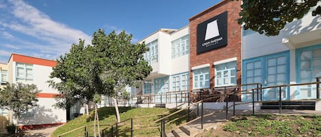 Un hotel con un letrero llamativo, una escalera y un área ajardinada con árboles.
