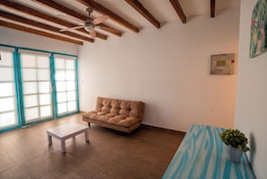 A room with a brown sofa, a small white table, and a ceiling fan. - Casa Andina Standard Ica   (Ica)