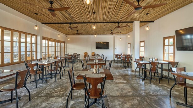 Un comedor amplio con techos altos, vigas de madera y varias mesas y sillas.