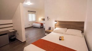 Una habitación de hotel con cama, mesita de noche y un pequeño escritorio con un cesto de basura.