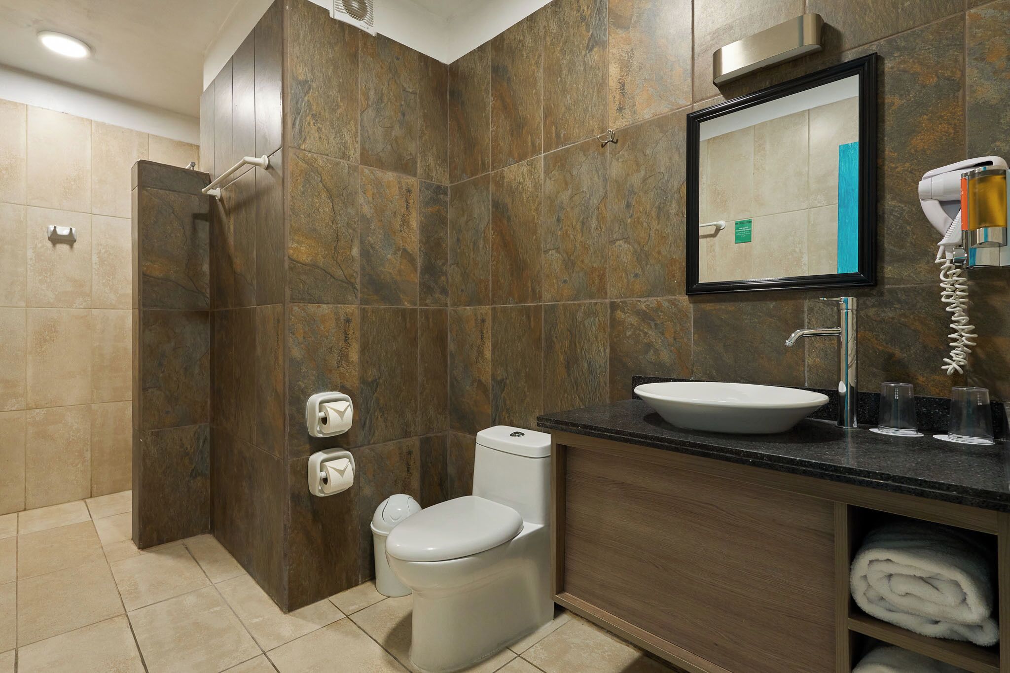 A modern bathroom with a shower, toilet, sink, and a mirror above the sink.