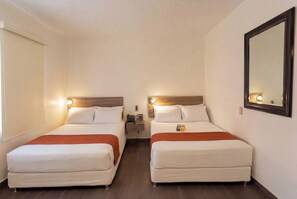 A hotel room with two beds, a nightstand, a mirror, and a window with blinds.