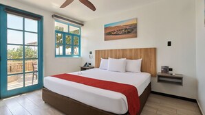 A hotel room with a large bed, a ceiling fan, a painting, and a view of the outdoors. - Casa Andina Standard Ica   (Ica)