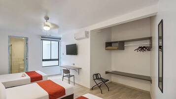 Una habitación de hotel moderna con cama, escritorio, silla, televisor y armario.