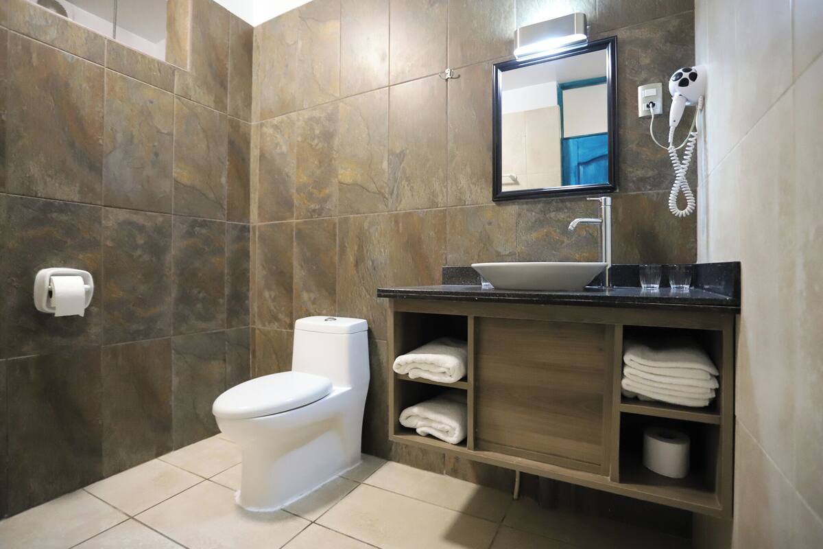 A bathroom with a toilet, sink, mirror, and towel storage.