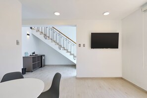 A modern interior with a staircase, a dining area, and a flat-screen TV mounted on the wall. - Casa Andina Standard Ica   (Ica)
