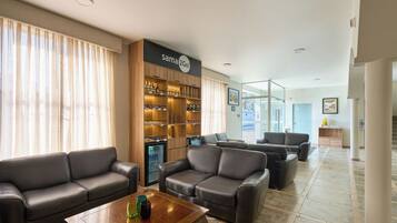 A hotel lobby with leather sofas, a coffee table, a minibar, and a Sam's Club sign.