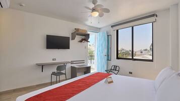 A hotel room with a bed, a desk, a chair, a television, and a large window.