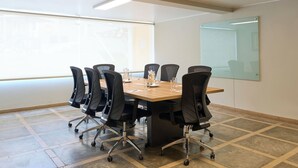 A conference room with a long table, black chairs, and a glass partition. - Casa Andina Standard Ica   (Ica)