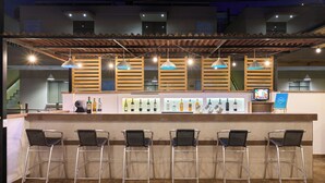 A bar area with a counter, bar stools, and a selection of bottles. - Casa Andina Standard Ica   (Ica)