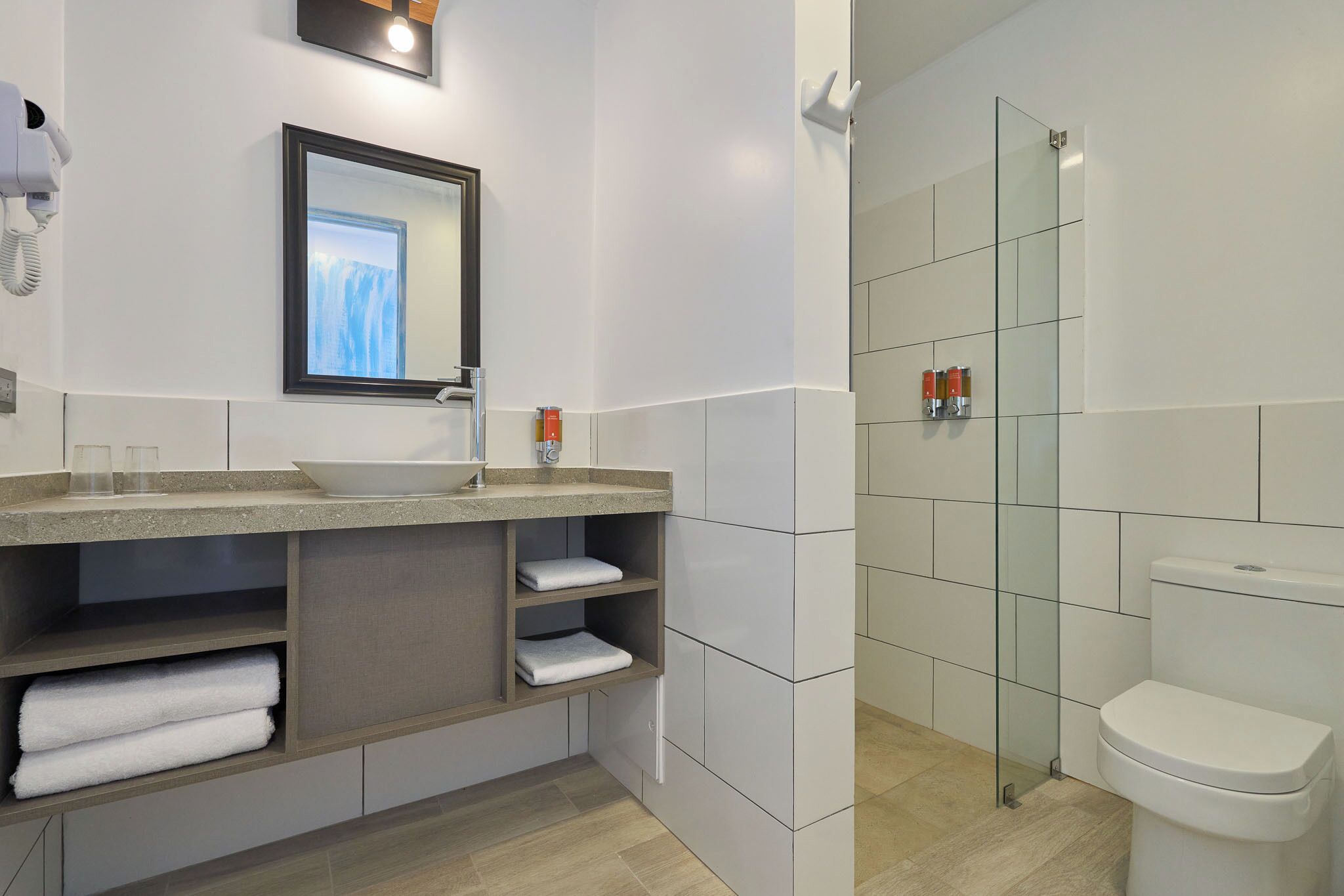 A modern bathroom with a glass shower enclosure, a sink with a mirror, and a toilet.