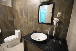 Un bagno con un water bianco, un lavandino con uno specchio sopra e un asciugacapelli montato alla parete.