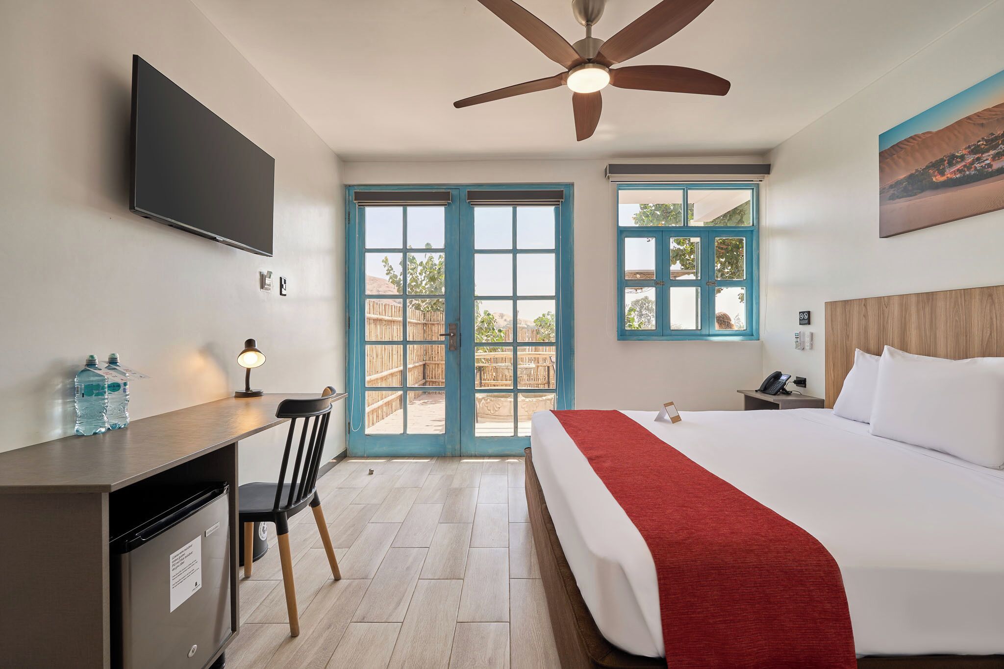Una habitación de hotel con cama, escritorio, silla y ventilador de techo.