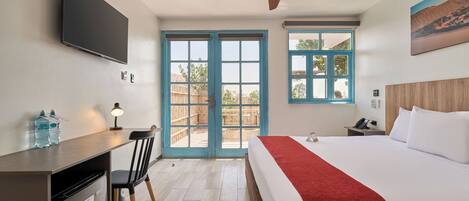 Una habitación de hotel con cama, escritorio, silla y ventilador de techo.
