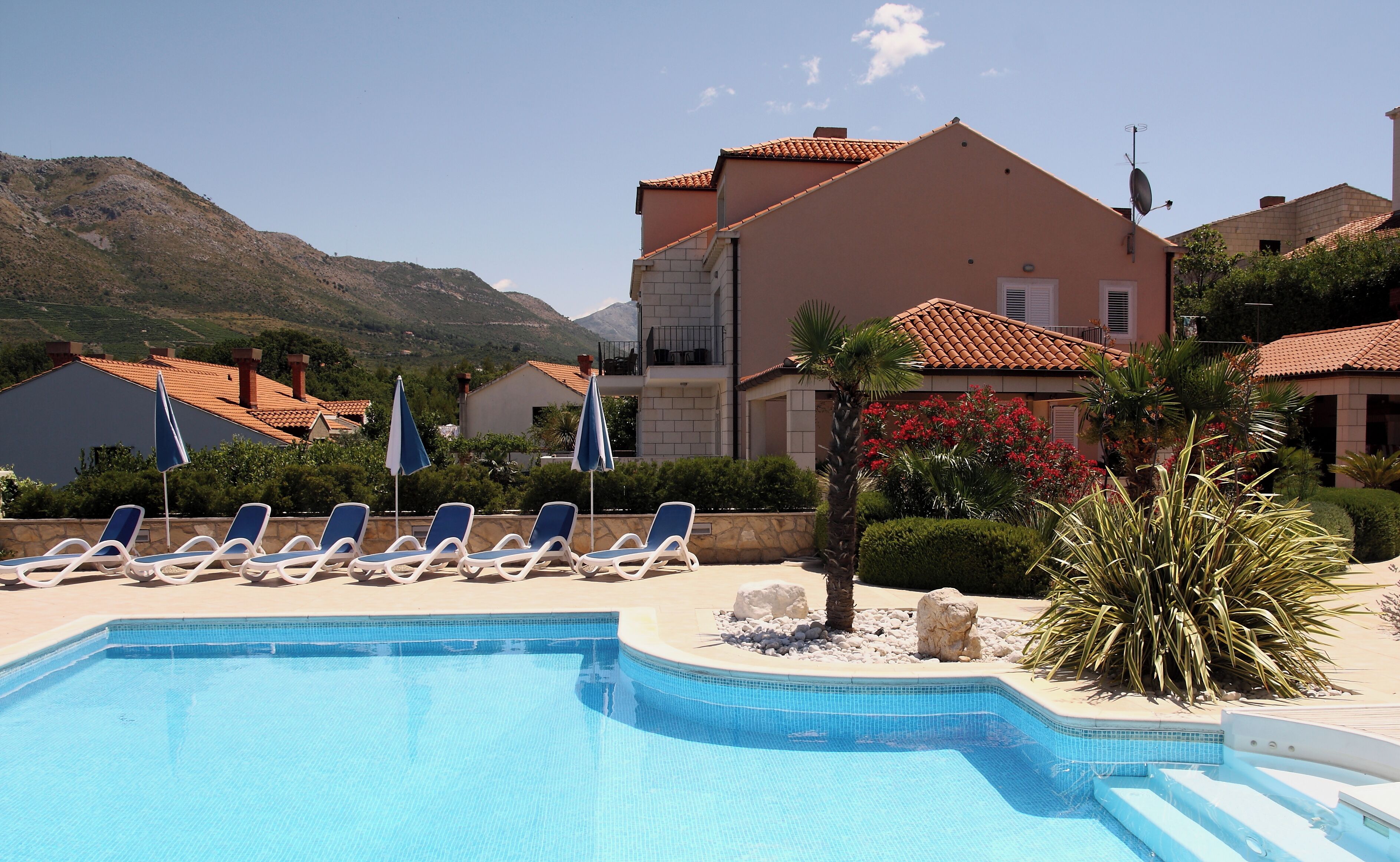 Zona de piscina con sillones de descanso y vistas a la montaña.