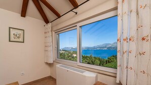 Una habitación con un ventanal grande que ofrece una vista panorámica del mar y las montañas.