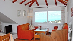 Una sala de estar acogedora con un sofá, sillones, una mesita y un televisor.