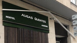 A hostel named "AUGAS QUENTES" with a green awning and a closed shutter. - Albergue Augas Quentes - Hostel (Ourense)