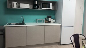 A compact kitchen with a sink, a microwave, a coffee maker, and a refrigerator. - Albergue Augas Quentes - Hostel (Ourense)