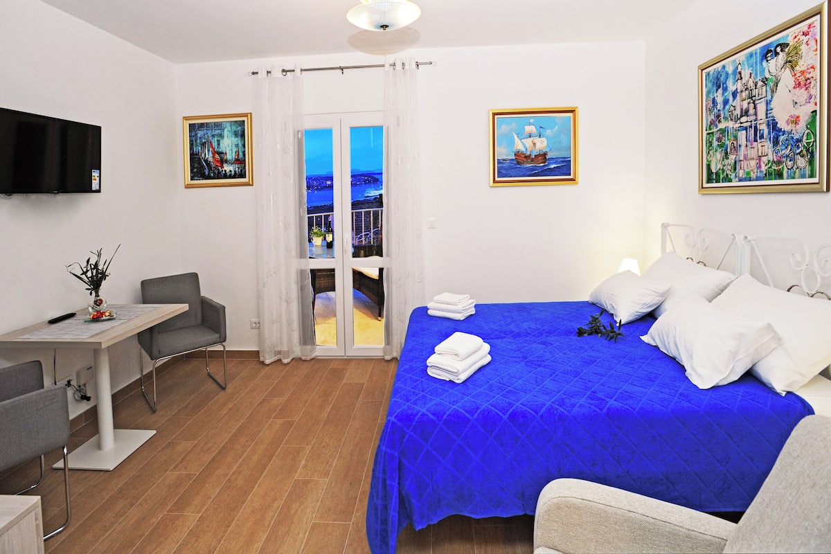 Une chambre d’hôtel avec un lit, un bureau, une chaise, une télévision et un balcon avec vue.