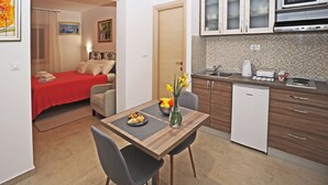 Ein kleines Hotelzimmer mit einer Küchenzeile, einem Essbereich und einem Bett.