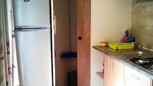 Een kleine keuken met een magnetron, een koelkast en een wastafel.