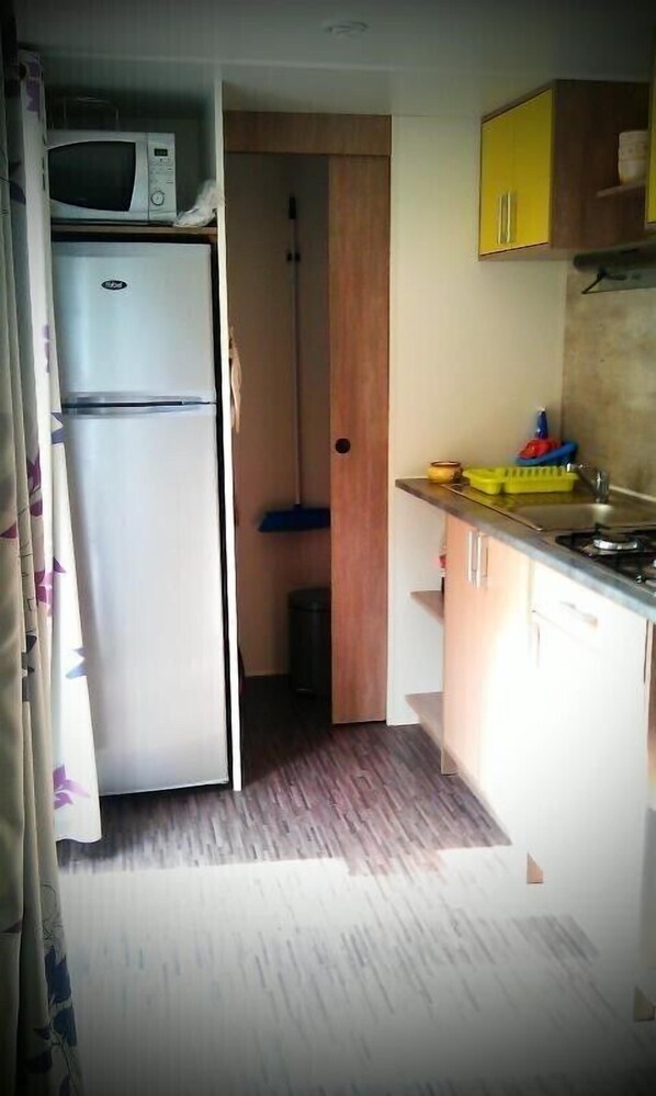 A compact kitchen with a microwave, a refrigerator, and a sink.