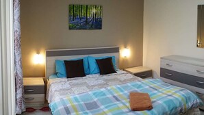 A bedroom with a bed, two bedside tables, a nightstand, a dresser, and a painting on the wall. - Flat in Gzira 2 minutes from the sea (Gzira)