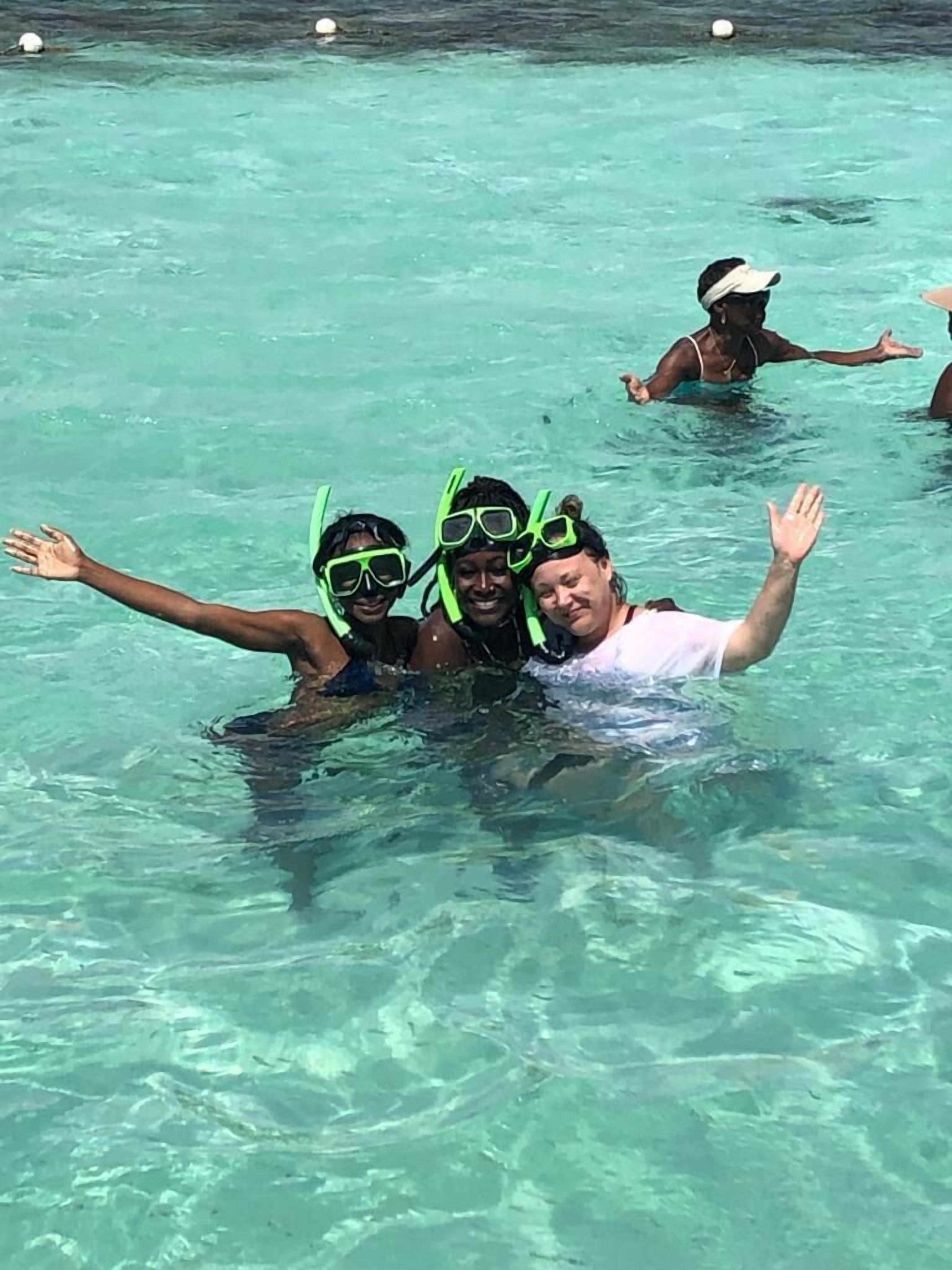 Un grupo de personas haciendo snorkel en aguas turquesas y transparentes.