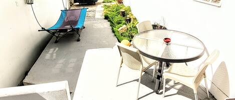 Un espace patio avec une table et des chaises, un fauteuil abrité et un barbecue.
