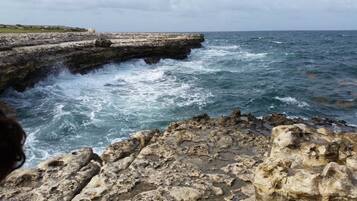 A rocky coastline with waves crashing against a stone structure.