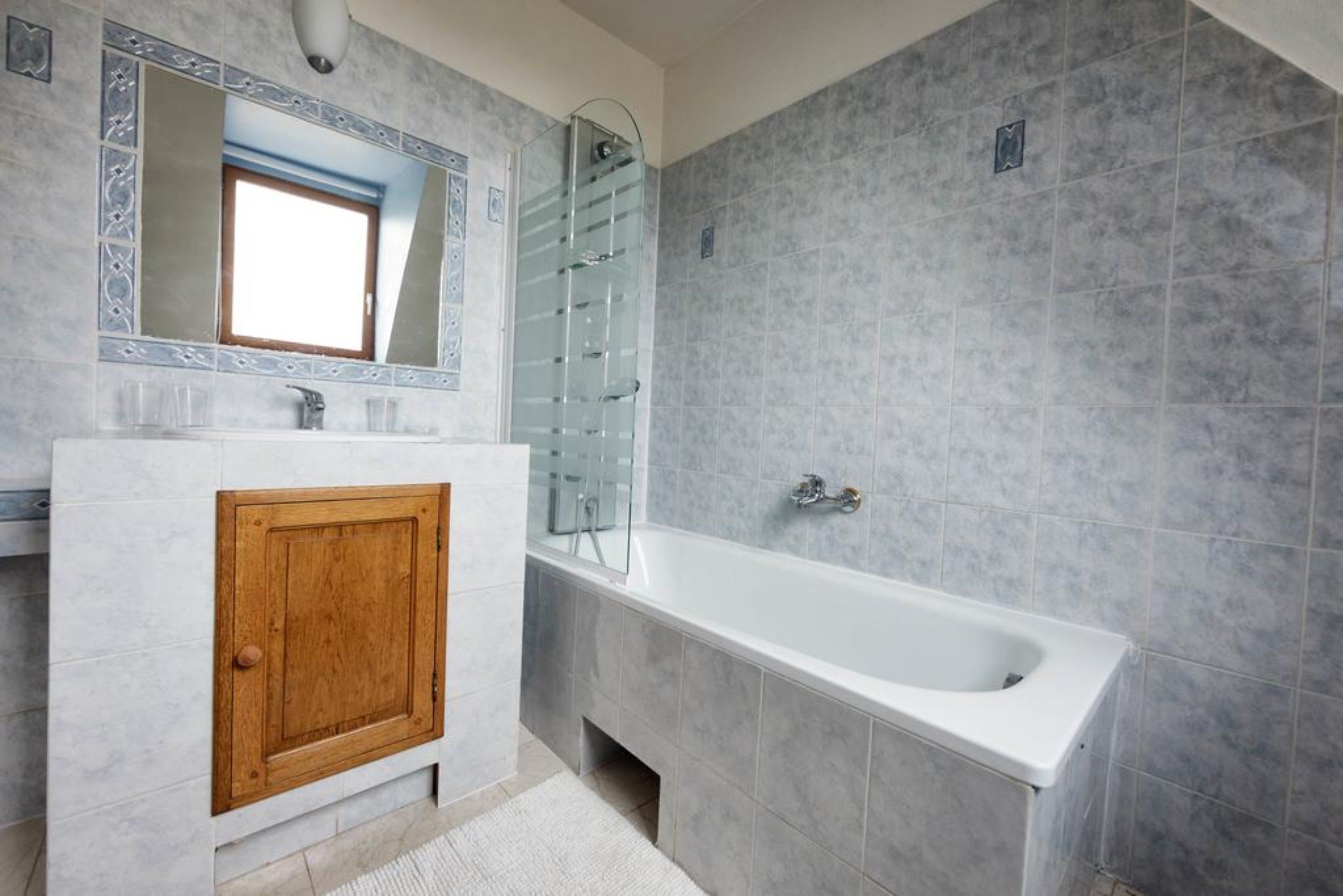 Un baño con tocador de madera, un espejo grande, una bañera y una cabina de ducha con paredes de vidrio.