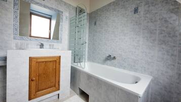 Un baño con tocador de madera, un espejo grande, una bañera y una cabina de ducha con paredes de vidrio.