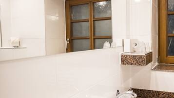 A modern bathroom with a white sink, granite countertop, and a mirror above it.