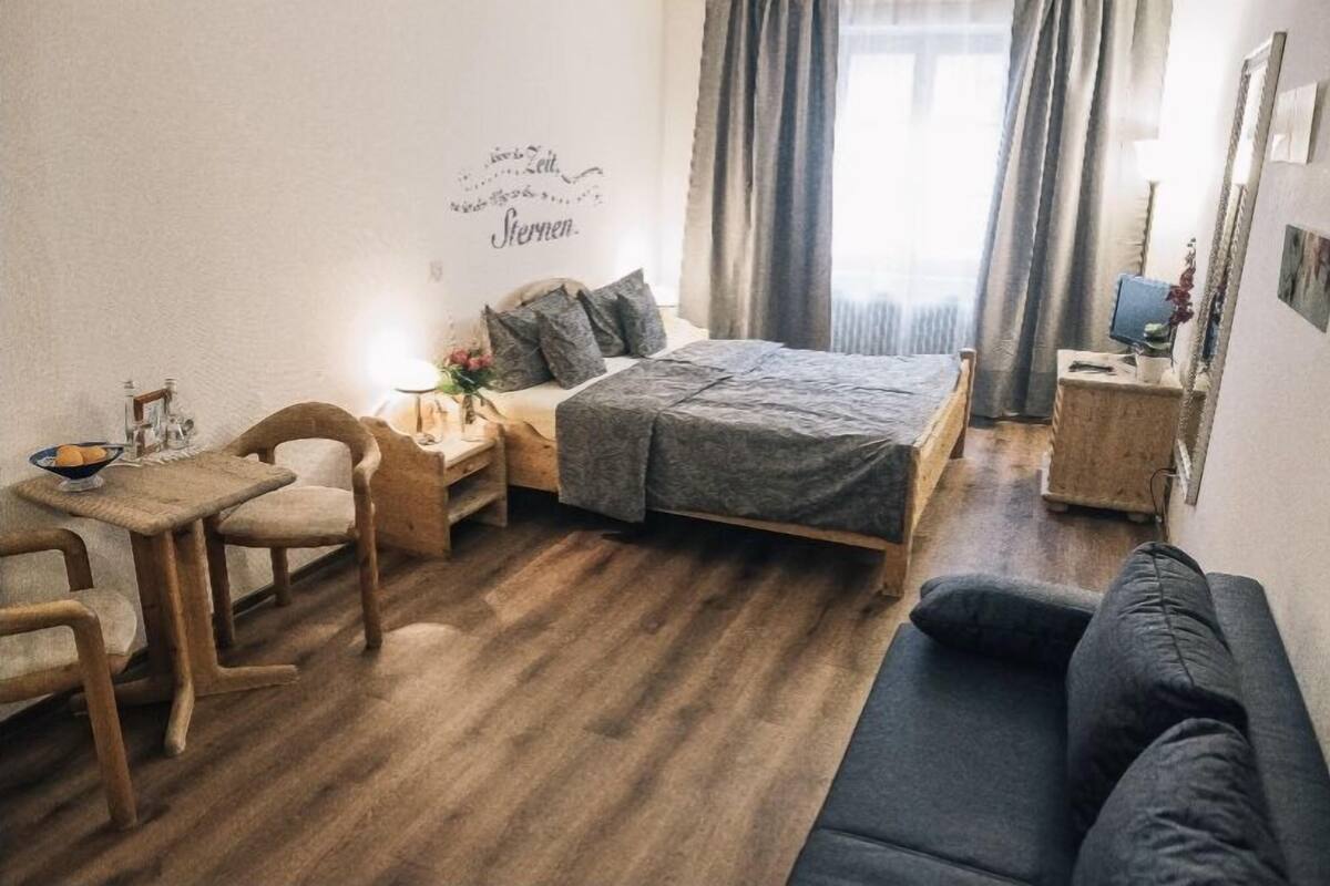 A cozy room with a bed, a small desk, a chair, and a sofa.