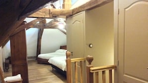 A bedroom with a wooden staircase, a bed, and a chair. - Domaine de Noyer (Saint-Christophe-en-Brionnais)