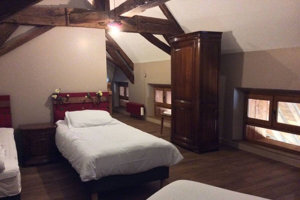 A bedroom with two beds, wooden furniture, and a sloped ceiling.
