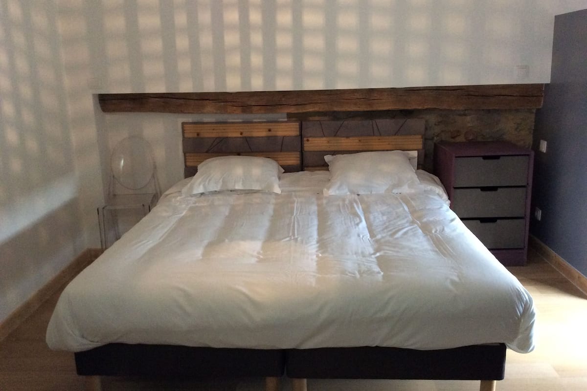 A bed with a wooden headboard, two pillows, and a bedside table with drawers.