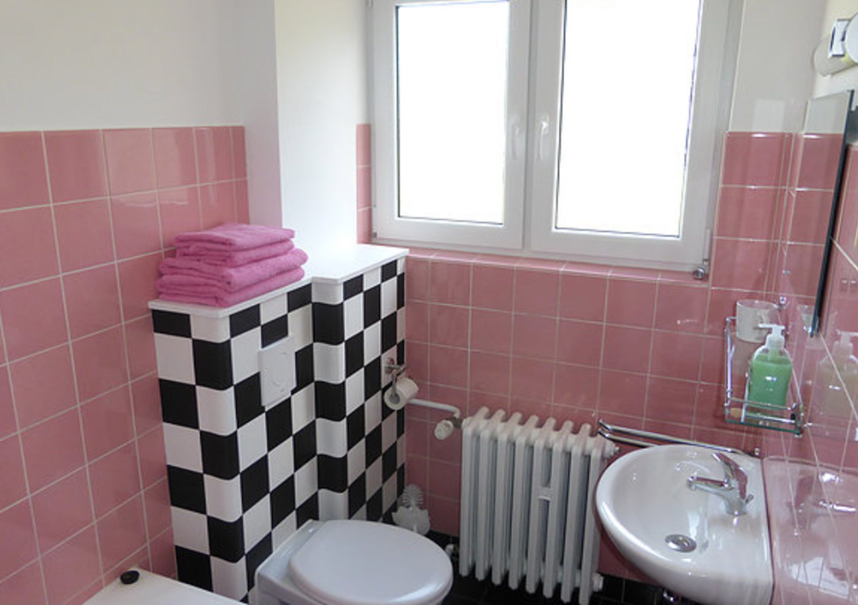 Ein Badezimmer mit karierter Wand, Toilette, Waschbecken und einem Fenster.