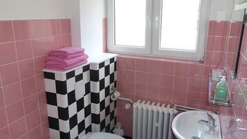 Ein Badezimmer mit karierter Wand, Toilette, Waschbecken und einem Fenster.